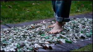 Man doing a walk over broken glasses thinking it is because of the power of mind