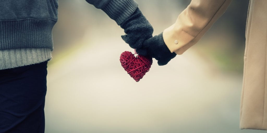 Partners celebrating happy relationships by walking hand in hand with a heart