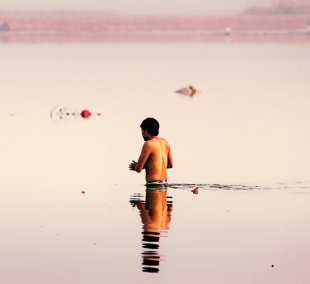 Man using the defense mechanism of magical undoing and taking a bath in river Ganga hoping his sins will be washed away