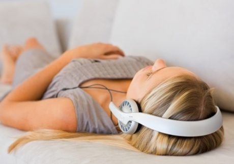 A girl lying down on a sofa listening to music to practice self hypnosis for relaxation