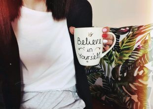 A girl holding the mug with a quote about believing in yourself